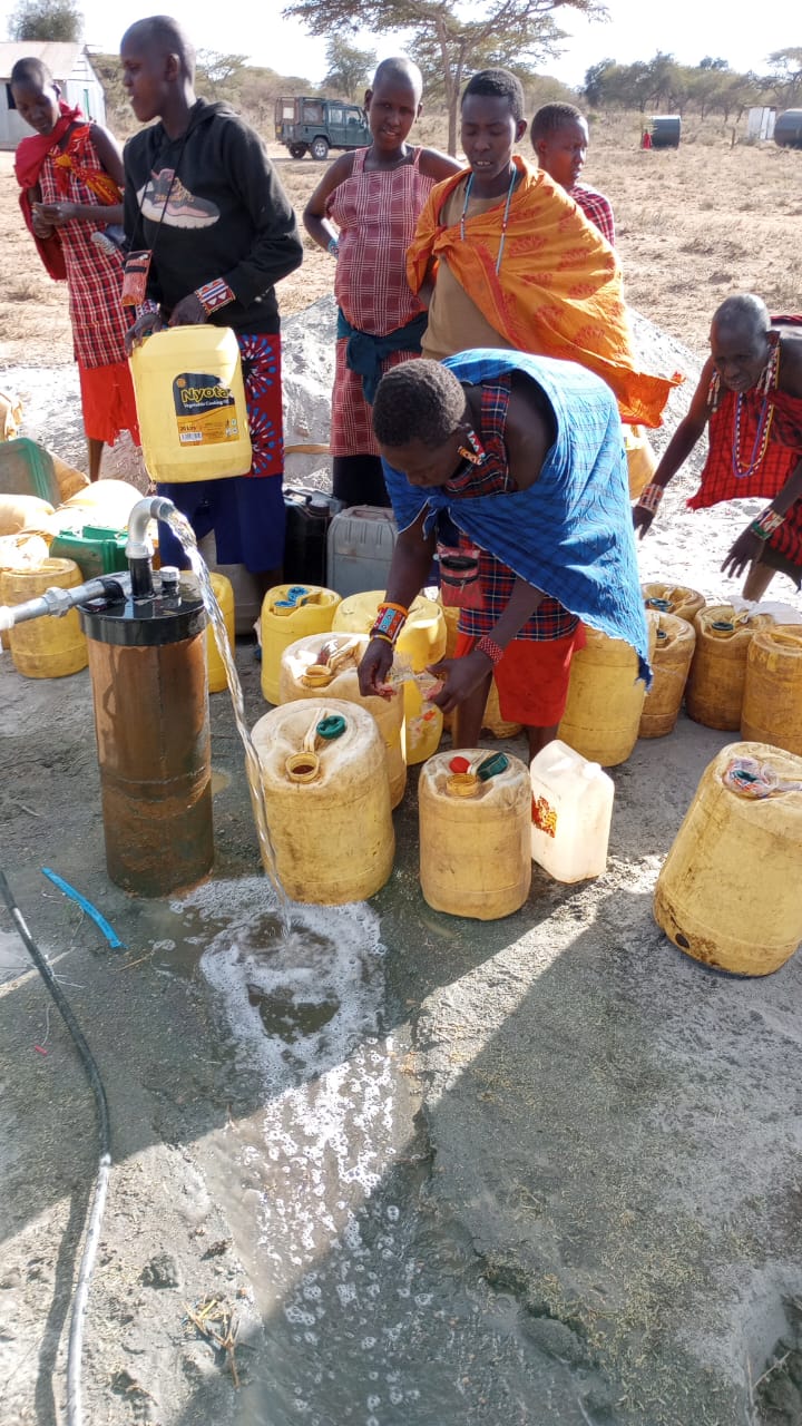 Maasai women and adolescent girls collecting clean drinking water from the borehole